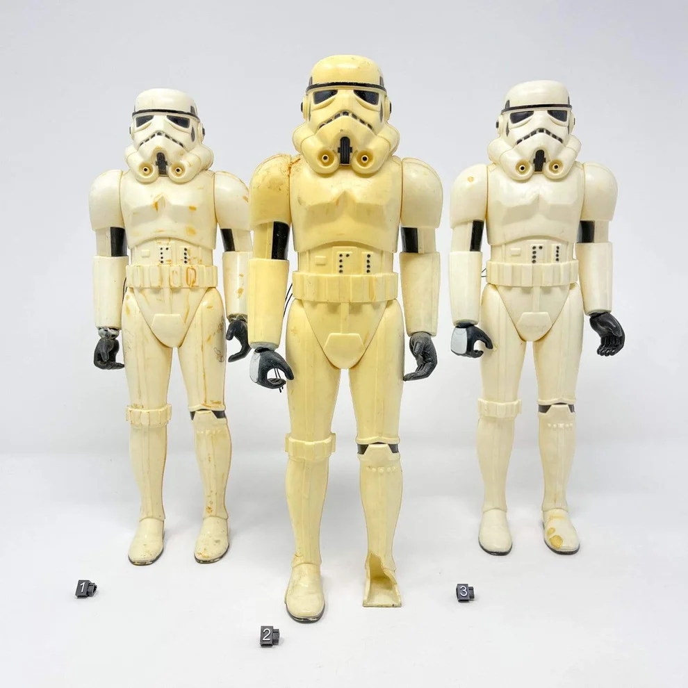 Image direction: material ageing rather than play wear - yellowed clear blister, cream/yellow white plastic, warped limb or tacky degrading soft plastic.