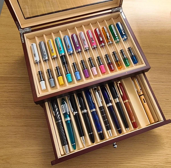 Image direction: careful storage or conservation of vintage pens showing trays, separation of materials or handling of fragile mechanisms. Avoid lifestyle desk photography.